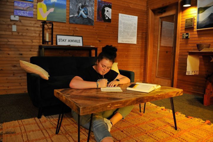 individualized studies student seated on floor, writing at low table