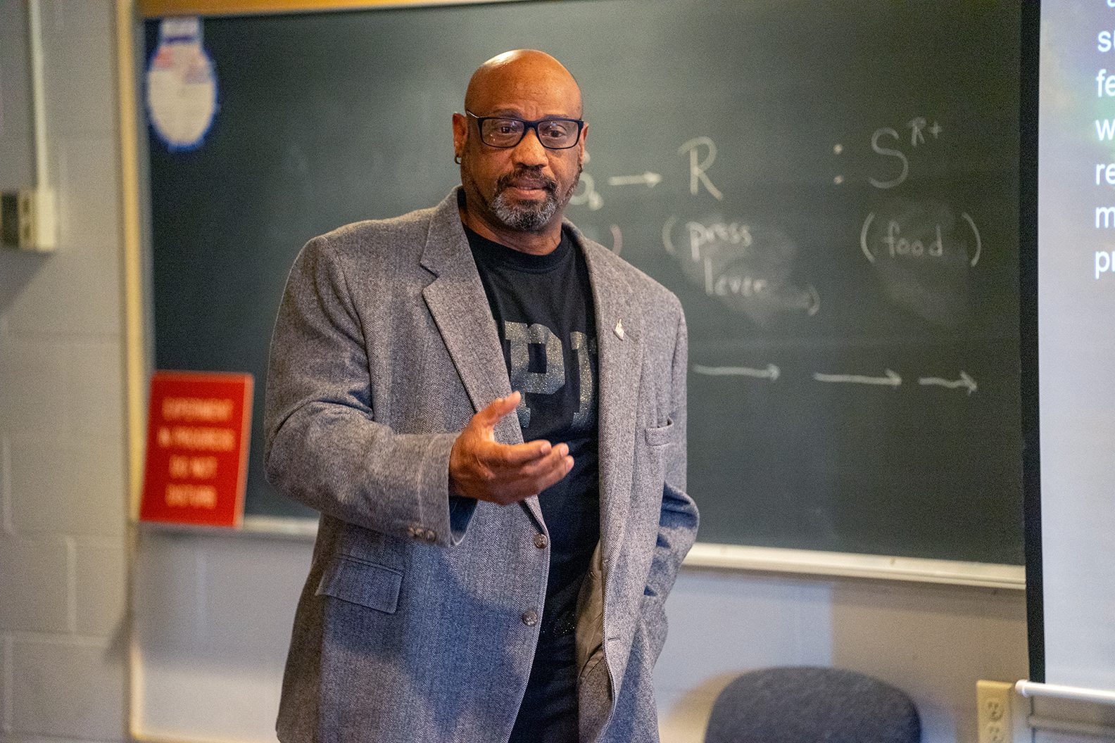 male teacher gesturing in front of chalkboard