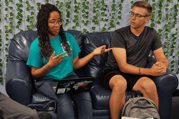 Male and female student sit on a couch in discussion