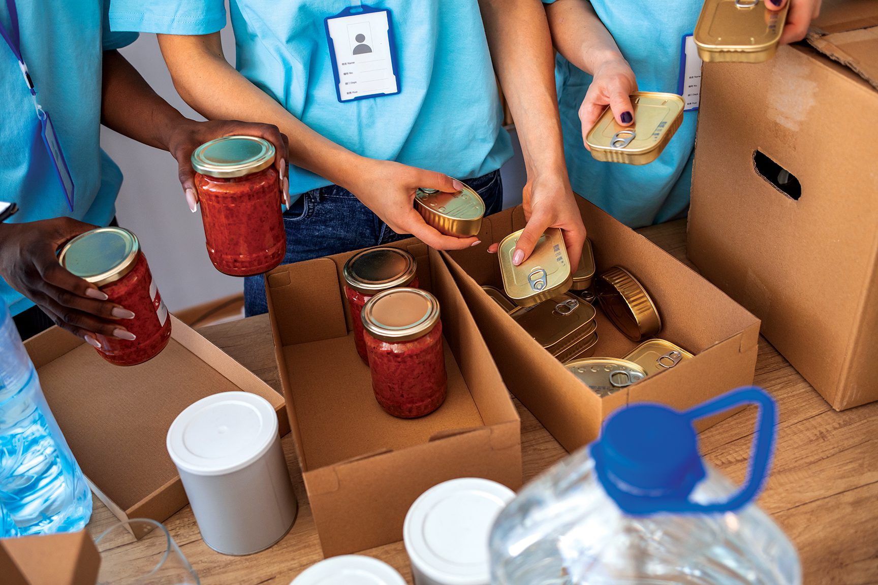 hands of msw program students filling cardboard boxes with food donations